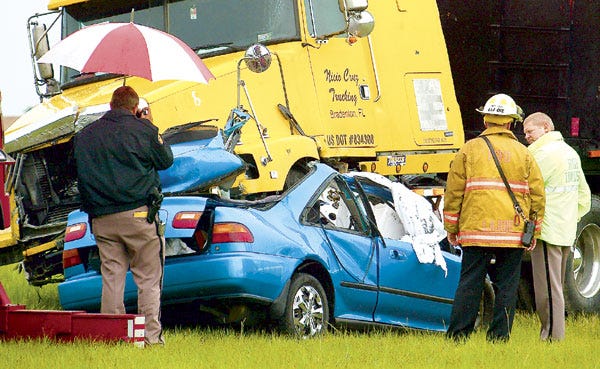 Emergency personnel investigate the scene in which a tractor-trailer collided with a Honda Civic on the Polk Parkway north of the Old Dixie Highway interchange in Auburndale on Tuesday. The Honda's two occupants died in the crash and have not been identified by the Florida Highway Patrol. Neither the truck's driver nor his passenger was injured.
