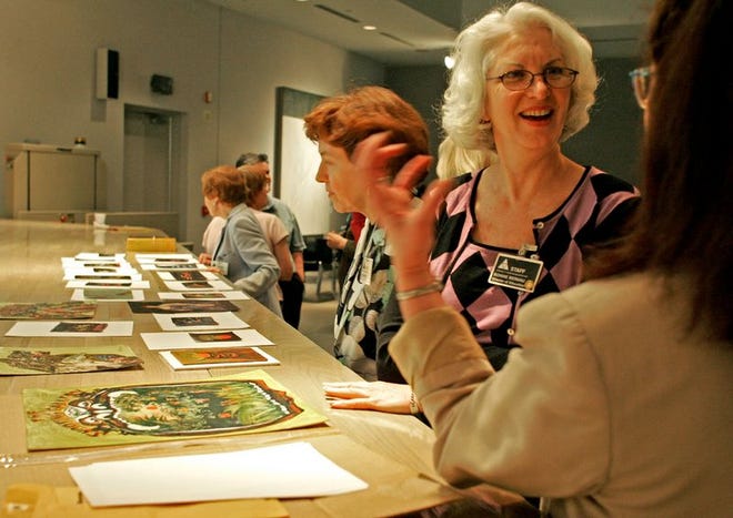 Harn Museum of Art director of education Bonnie Bernau, at right facing, and Harn docent emeritus Deborah Cohen-Crown, far right, discuss artwork by Arnold Meches during a docent meeting in April. Jackie Friel, a Harn Museum docent, explains the paintings on display.