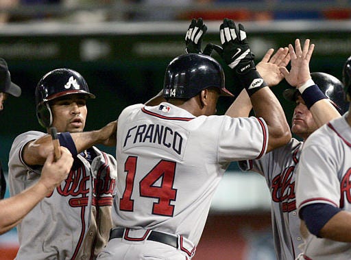 Atlanta's Julio Franco is greeted at home plate by teammates Rafael Furcal, left, and Marcus Giles after Franco hit a grand slam off Florida reliever Valerio De Los Santos in the eighth inning Monday in Miami.