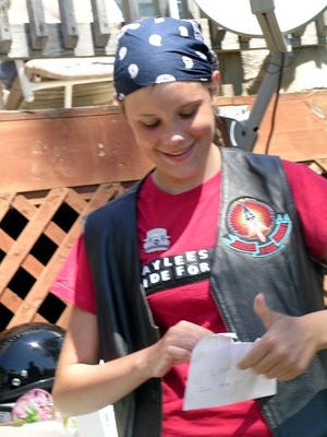 KAYLEE CASSAVAUGH, clad in borrowed biker regalia, opens a card from Bob Pease and the Capital Region's Bikers for Christ. Cassavaugh also received a biker teddy bear at a fundraising event Saturday.