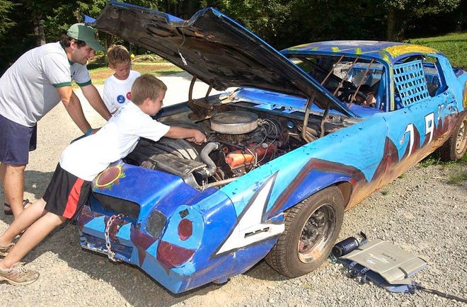 Camp Arrowhead counselor Jim Ligori, left, and James Allen, 9, Jackson Corter, 11, look under the hood of a 1978 Camaro that boys at the campground have rebuilt.