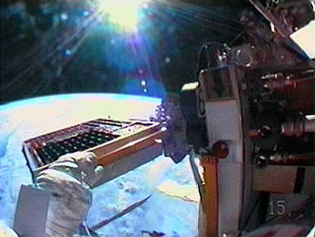 A camera attached to Japanese astronaut Soichi Noguchi 's helmet gives a view of an experiment, left side of frame under Noguchi's hand, after its' installation on the exterior of International space station Wednesday, Aug. 3, 2005.