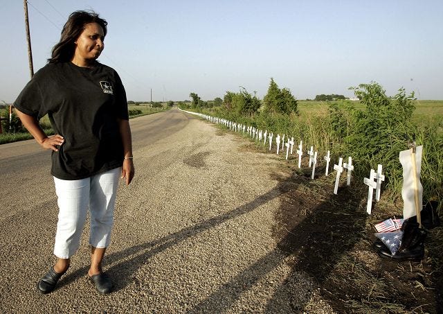 Barbara Porchia of Camden, Ark., looks at some of the nearly thousand crosses that sit by a roadside camp near President Bush's ranch, Thursday, Aug. 11, 2005, in Crawford, Texas. Porchia, who's son, Jonathan Cheatham, died on July 26, 2003 during the Iraq war, arrived at the location Thursday in support of the anti-war protest. (AP Photo/Tony Gutierrez)