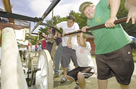 Joseph LaMarche, far right, joins a crew helping build water pressure in the pumps of the Granite, one of a dozen handtub fire engines competing in the longest-distance-covered spraying event during the 33rd annual Newmarket Old Home Days celebration on Saturday. Events continue today.