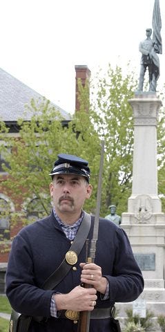 Dan Meehan of the Charles W. Canney Camp 5, Sons of the Union Veterans of the Civil Warm poses in front of Dover's Civil War monument by the Public Library.