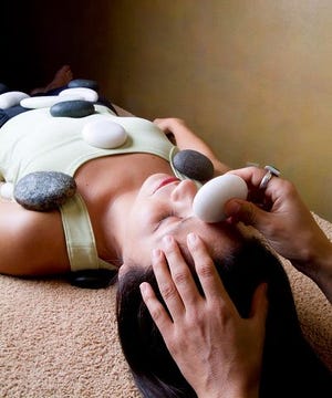 A model is given a therapeutic stone massage using heated black basalt stones and cool white marble stones at the Miraval Life in Balance Spa in Catalina, Ariz.