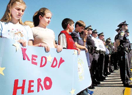 Students from Sanborn Middle School held handmade signs in support of officer Melvin Keddy, who was killed 10 years ago by a drunken driver. From left are Kayla Souce, 12, Nicole Lopez, 13, Polan Freinhofer, 12, and Ben Giorgi, 12. The Melvin A. Keddy Memorial Highway dedication ceremony took place on Route 125 in Kingston on Wednesday.