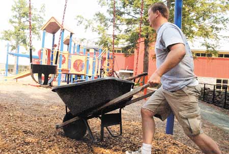 PixelMedia employee Jeff Sansone carries a load of mulch to spread at the Community Campus playground in Portsmouth as part of the United Way?s Day of Caring on Wednesday.