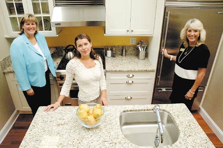 Prudential Rush Realty officials, from left, Cindy Winthrop, Martha Baroody and Kathy Rush, in a kitchen model Tuesday afternoon, are part of a team that has sold 70 percent of the Harbour Hill condo complex, currently being constructed on Hanover Street.