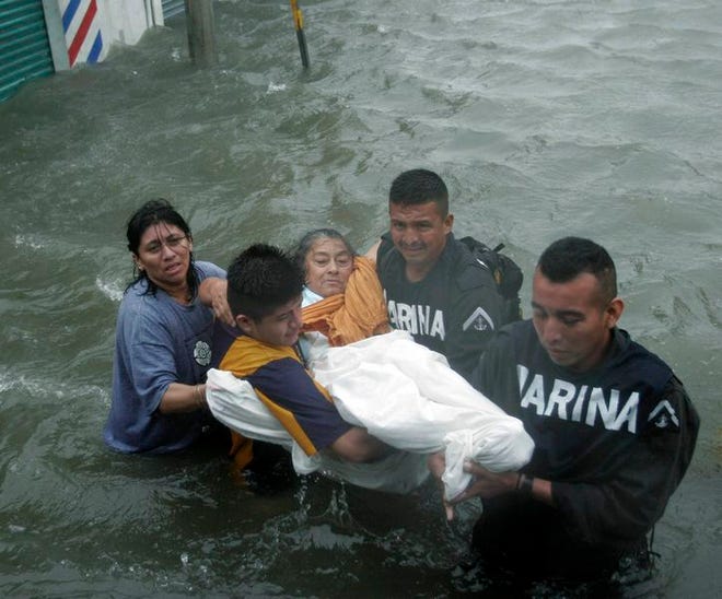 Members of Mexico's Marine Corps rescue a woman from her flooded home in Cancun, Mexico, on Saturday.