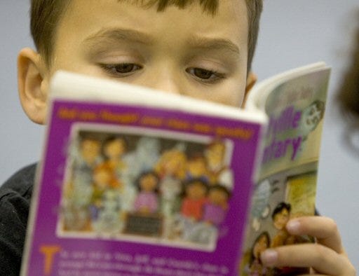 Jacob Southall, 7, a second grade student at The Villages Elementary School, reads one of the 100 books that members of the Kiwanis Club of Lady Lake handed out to students to keep as part of RIF, Reading is Fundamental.