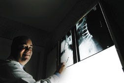 Christopher Cenac Jr., a third- generation surgeon, inspects X-rays at his Houma office.
