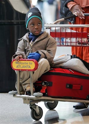 Demaine Williams, 5, rides on a luggage cart at Hartsfield Jackson Atlanta International Airport. Officials expected 285,000 people to pass through the airport Tuesday.