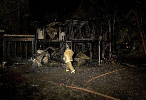 A firefighter investigates an early morning fatal house fire Tuesday morning in Ocala.