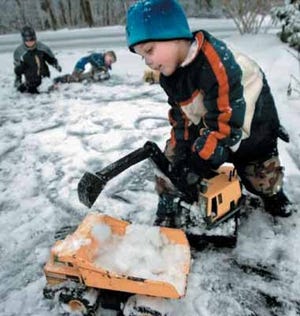 Five-year-old Ryan Curry, right, uses his toy truck to help clear some snow from the driveway of his parents' Price Township home with his friend Kyle Smith, 6, far left, and brother Colin Curry, 6, Monday.
