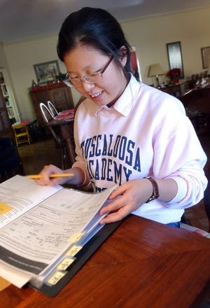 Jin Joo Shim sorts through her file of college information Friday at her host family’s house in Northport. Shim is a senior at Tuscaloosa Academy and lives with Margaret Conger, academic dean at TA. Originally from South Korea, she is applying to 13 American universities. Shim spent much of her holiday break preparing applications for college.