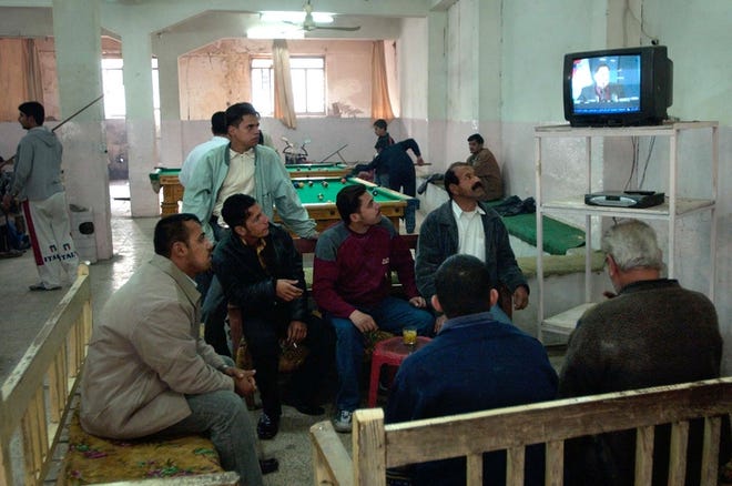 Iraqis watch election official Safwat Rasheed read the Dec. 15 parliamentary election results on TV in a pool hall Friday in Baqouba, Iraq.