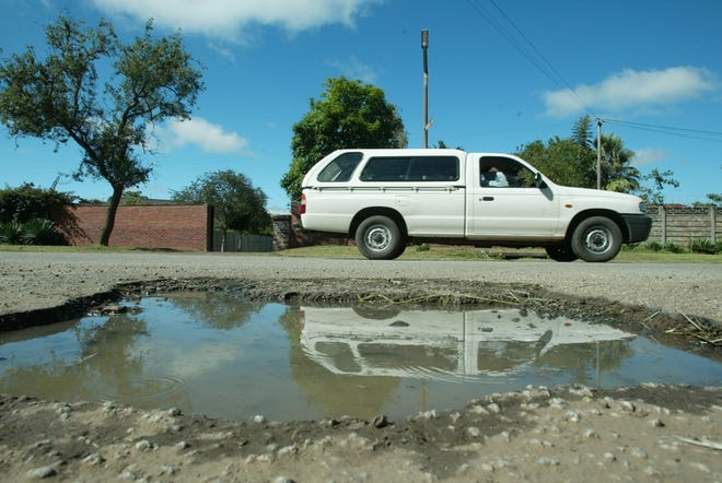A motorist drives past an unrepaired pothole in Harare, Zimbabwe, on Friday. Authorities say they do not have the manpower or gas to mobilize sufficient road repair crews.