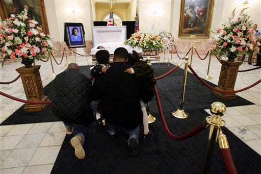Gary Allen Jr., left, and Robert Washington holding his two children, Robert Washington II, 2, left, and Sierra Washington, 4, right, kneel as they pay their respects as Coretta Scott King lies in honor in the Rotunda at the Capitol in Atlanta Saturday, Feb. 4, 2006.