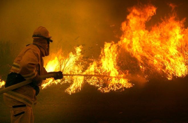 Santa Ana firefighter Ron Lara shoots water on a fire burning in the median of a toll road near Anaheim, Calif., on Monday.