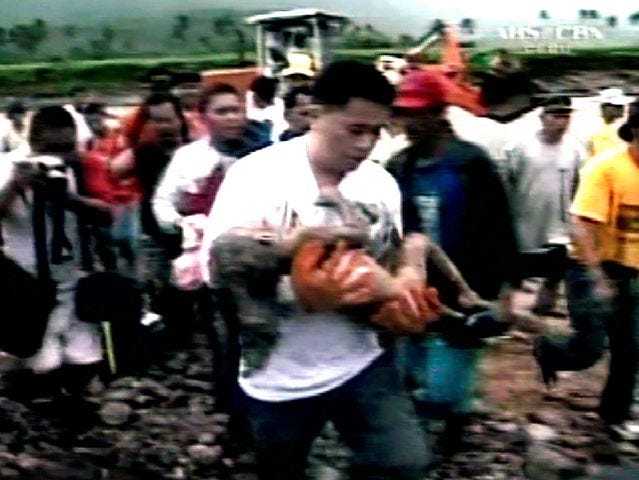 A small child is carried from a landslide on Leyte island in the eastern Philippines Friday, Feb. 17, 2006. A rain-soaked mountainside disintegrated into a torrent of mud on Friday, burying hundreds of houses and an elementary school in the eastern Philippines. Ten people were confirmed dead, and at least 1,500 were missing. (AP Photo/ABS CBN via APTN)