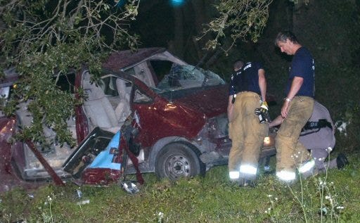 Marion County Fire-Rescue firefighters and Florida Highway Patrol troopers examine a van that crashed off I-75 north of Ocala on Tuesday.