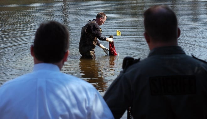 Forensics investigator David Hogsed with the Spartanburg County Sheriff's

Department retrieves an article of clothing from the pond near where Jeffrey

Hubbard was found dead.
