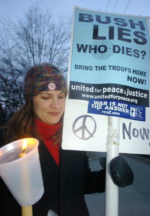 Christine Griffen holds a candle and poster during a peaceful demonstration at the Monroe County Courthouse in Stroudsburg on Sunday.