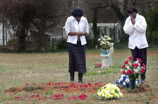 Alex Davon Buckman's sister LaCresha Stanton, left, and mother, Genevieve Buckman, stand at his graveside at the Collins Cemetery.