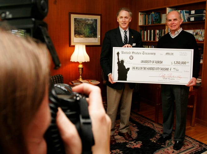 U.S. Rep. Cliff Stearns and University of Florida President Bernie Machen pose Tuesday for University Photographer Kristen Bartlett as Stearns presents a $1.25 million check to the school.