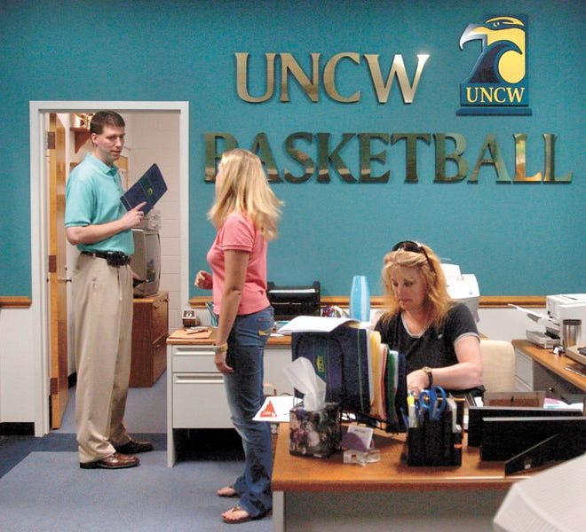 Newly hired UNCW men's basketball Head Coach Benny Moss (eft) talks with assistant team manager Liz Flora (center) and secretary Carol Stevens (right) Friday during his first official day on the job in Trask Coliseum.