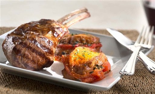 This photo provided by the American Lamb Board shows Grilled Double Lamb Chops With Tomato-Bread Pudding, a new lamb recipe from chef Geoffrey Zakarian. It's a recipe to give the home grilling team a chance to show off its skills, but it's not a hard workout. The lamb is cooked on the grill, then complemented with the savory side dish of fresh tomatoes and bread.