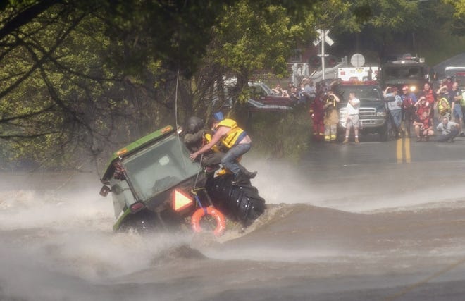 A man is rescued by a member of the National Guard, who was lowered from a helicopter, after the tractor he was operating was washed off the road Wednesday in Shoemakersville, Pa.