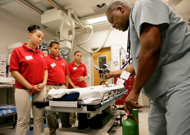 Shands at UF critical care technician Aaron Hunt demonstrates replacing an oxygen tank Wednesday morning in a trauma room in the ER to Gainesville High students, from left, Candice Williams, Rodrick Thompson and Lakeisha Hawkins.