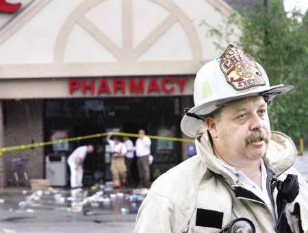 Exeter Fire Chief Brian Comeau talks with media representatives outside of the Walgreens where the roof collapsed in Tuesday's severe storms.