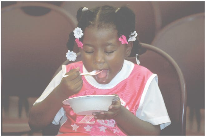 Three-year-old Princess Moore eats ice cream Thursday at the Maya Angelou Branch Library in Stockton, where about 50 people turned out for an ice cream social marking the end of the library’s summer reading program.
