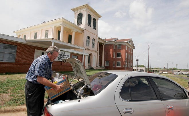 Volunteer Bobby May takes a load of food out to a client’s car at the Christian Ministry Center on 17th Street on Thursday.
