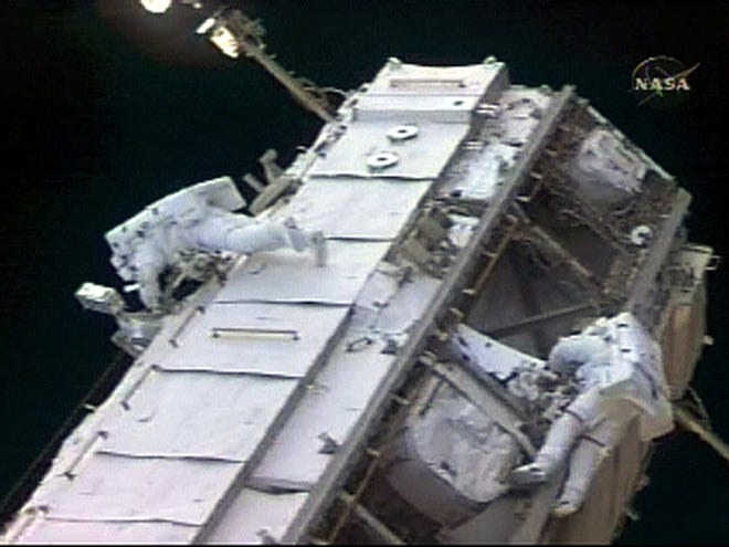 In this image made from NASA TV, German astronaut Thomas Reiter, left, and astronaut Jeff Williams, right, work on the truss of the International Space Station during a televised spacewalk Thursday