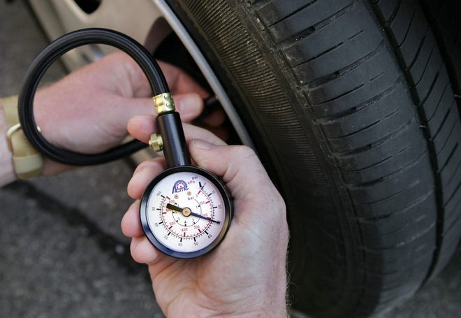 A motorist uses a gauge to check air pressure in a tire July 29 in Portland, Maine. Some motorists are inflating their tires with nitrogen instead of air because nitrogen-filled tires maintains pressure longer and may improve gas mileage.