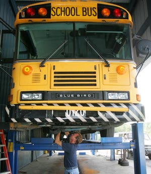 Bill Surman works on the air-conditioning unit of a 2001 Blue Bird school bus at the Northwest Transportation Complex on Old Gainesville Road on Friday.