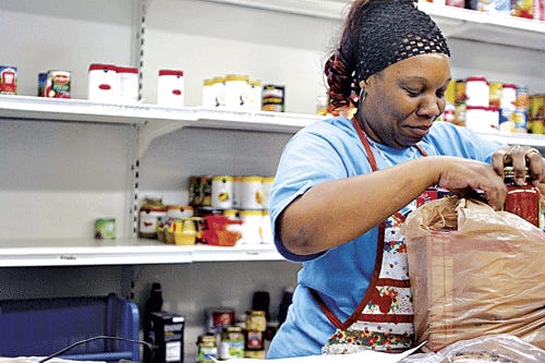 Dedra Gibson, a pantry assistant at Gainesville Community Ministry's food pantry, fills a bag with food for a person in need on Friday. The food pantry helps feed low-income and homeless people in the area but the amount of donated food drops during the summer leaving some shelves poorly stocked or even empty.