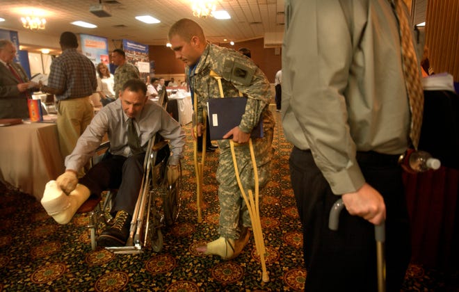 Army Spc. Jerome Williams, center, of the Florida National Guard compares injuries with Cpl. Eisen Kurt, left, of the Georgia National Guard, Wednesday Aug. 9, 2006, during a job fair for wounded soldiers at Fort Gordon, Ga. Both Kurt and Williams where injured during training and are being treated at the Army hospital at Ft. Gordon. Several government agencies jointly provided a workshop and career counseling to wounded soldiers from Army posts in Georgia and South Carolina. (AP Photo/Stephen Morton)