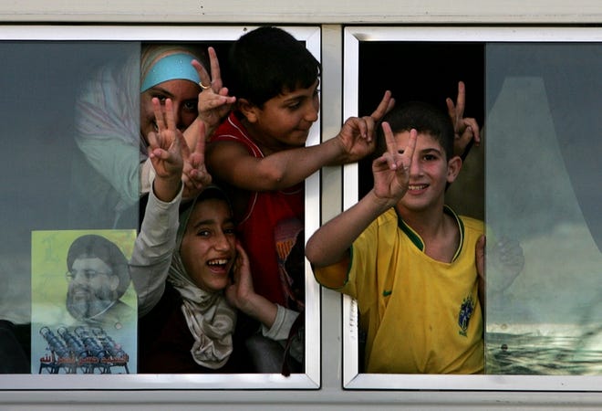 Lebanese children flash V for Victory signs as they head back to southern Lebanon on Monday. Hours after a U.N.-brokered cease-fire took hold Monday, thousands of refugees returned to check on their homes.