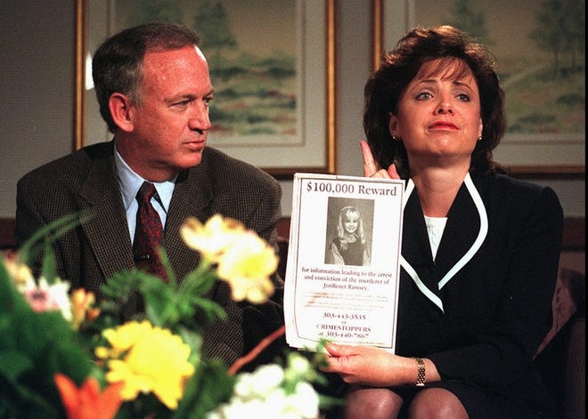 John Ramsey, left, looks on as his wife, Patsy, holds an advertisement promising a reward for information leading to an arrest and conviction in the murder of 6-year-old JonBenet in this May 1, 1997 photo.