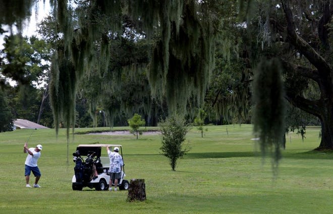 Gary Douglas, left, takes a shot on the par 4, 18th hole, while Douglas altman watches Monday at the Palatka Golf Club.