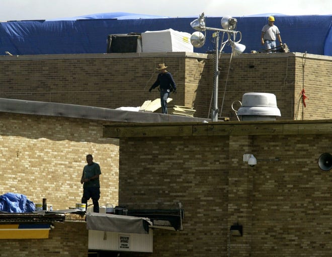 Roofers continue their work yesterday at Newburgh Free Academy, replacing about 4 acres of roof at one of many projects in the Newburgh School District. Despite wild rumors circulating around the district, the school will open on time on Sept. 5