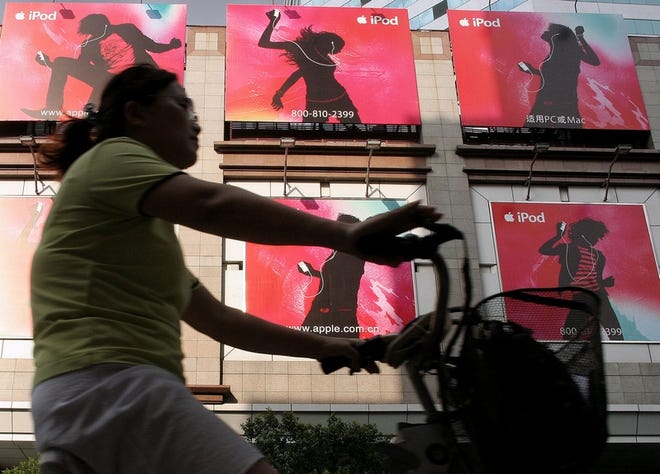 A woman rides a bicycle past advertisements of Apple Computer's iPod on Aug. 18 in Shanghai, China. Apple Computer said Wednesday it was working to resolve a dispute about alleged labor abuses by an iPod manufacturer in China.