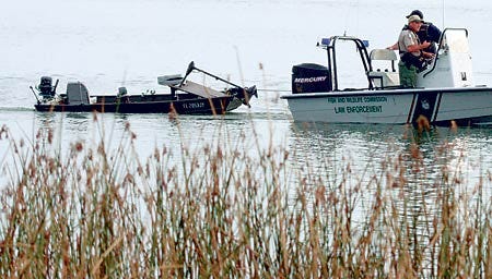 Officials tow a boat that capsized early Monday in Lake Parker. The body of James Sion, who had been in the boat, was found in the water near it.