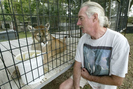 Darryl Atkinson shares a look with Roman, a cougar, whose cage is also too small, according to state guidelines.