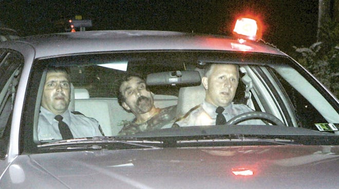 Officers transport Ralph “Bucky” Phillips, center, yesterday after he was captured in Akeley, Pa.